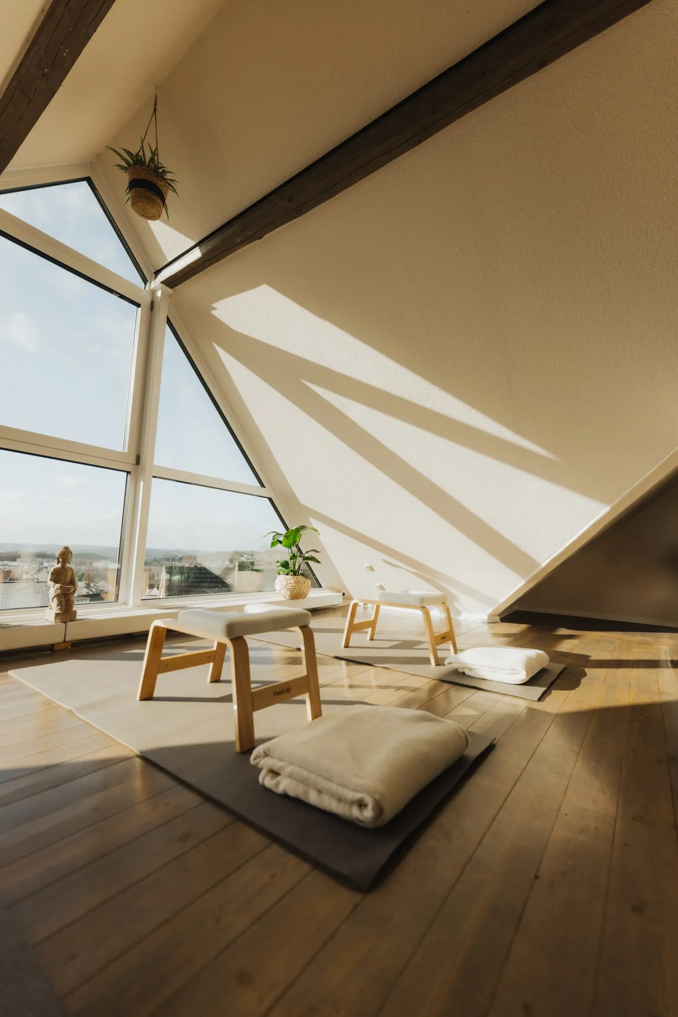 Hocker und Kissen vor dem großen Giebelfenster im Sonnenlicht