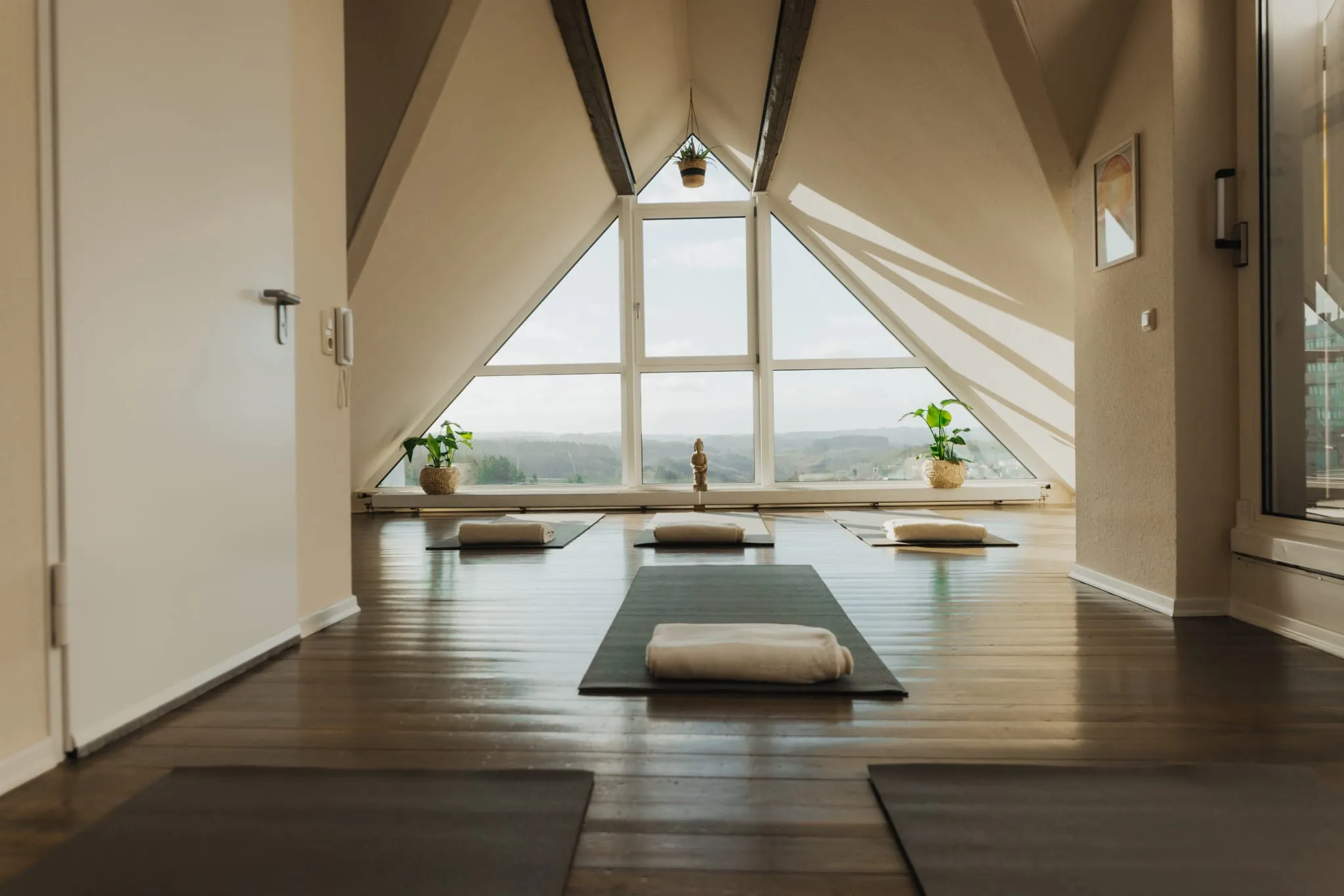 Yogamatten mit Kissen vor dem Giebelfenster des Yogastudios